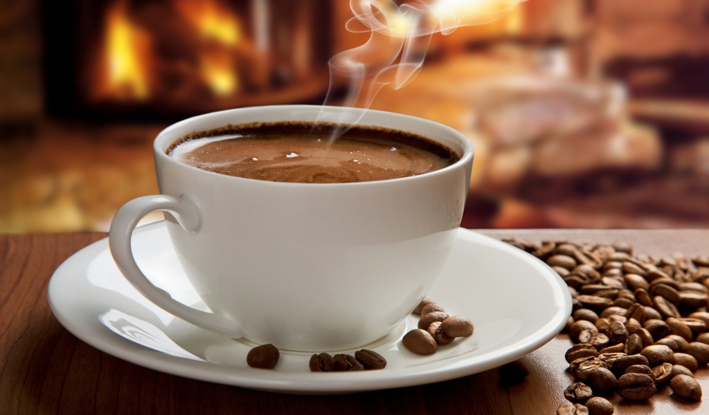 Большая белая чашка с горячим кофе на столе с кофейными зернами