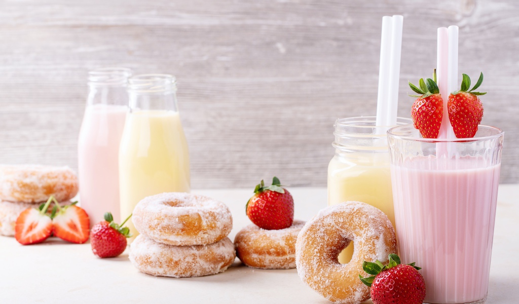 Молочные коктейли на столе с клубникой и пончиками