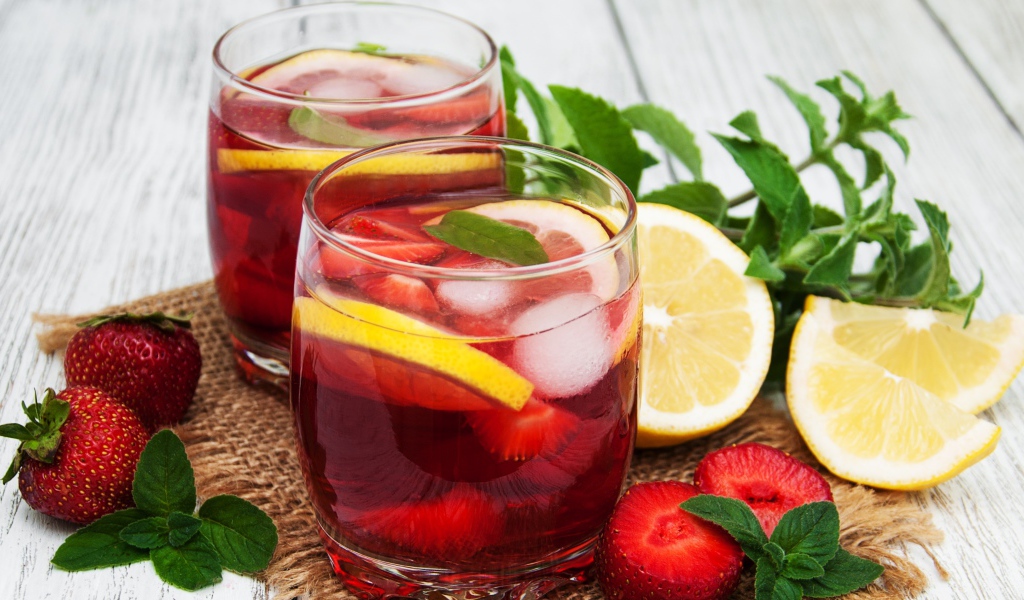 Мохито в стаканах на столе с клубникой, лимоном и мятой