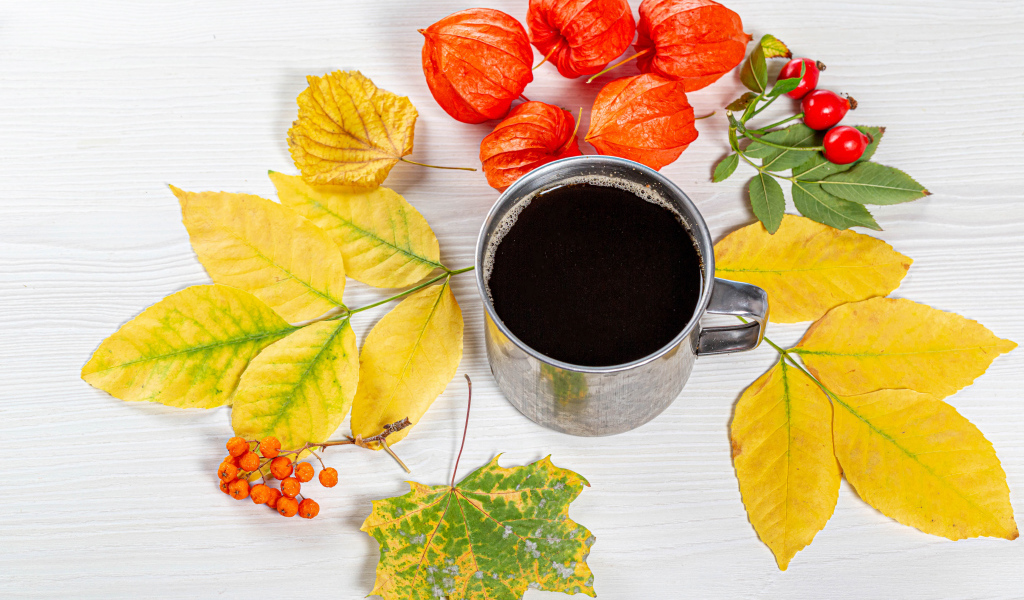 Кружка кофе на столе с осенними листьями, физалисом и шиповником