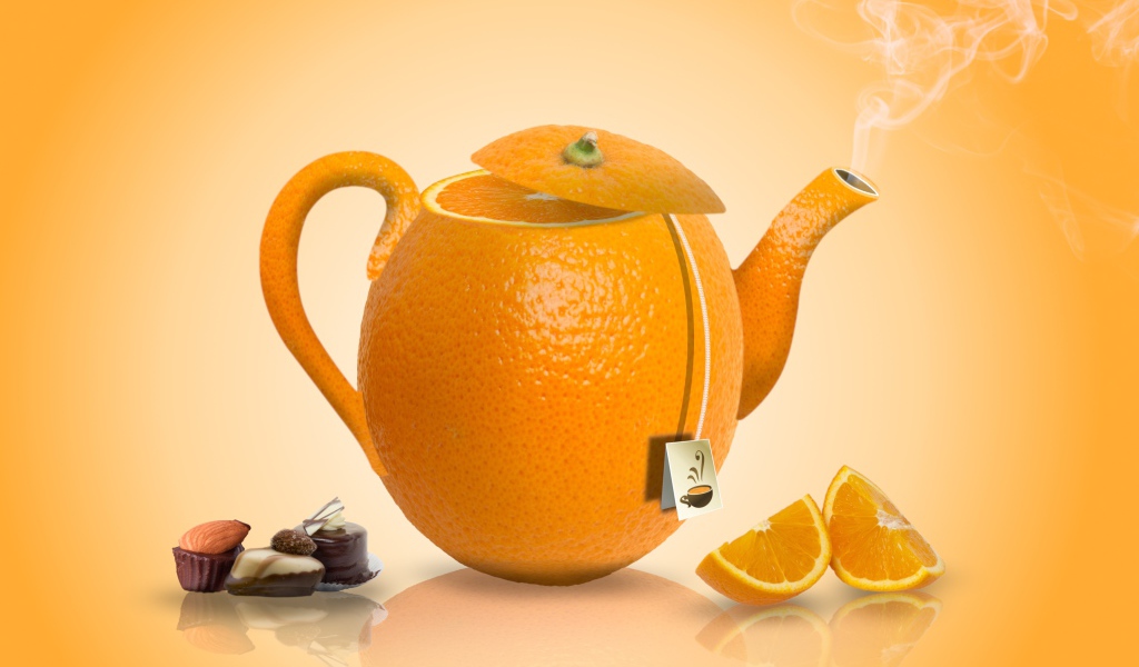 Чайник апельсин на оранжевом фоне с конфетами