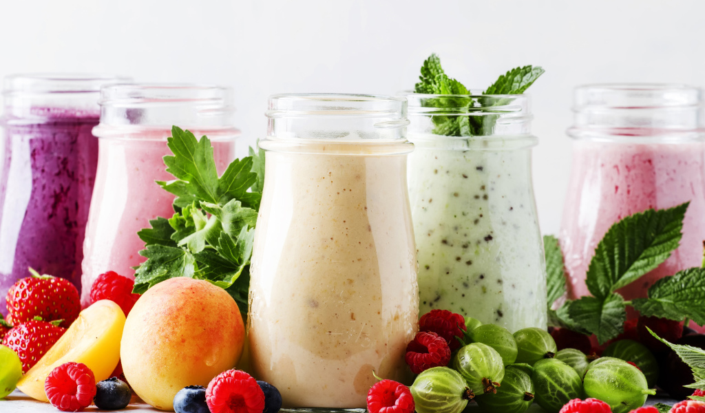 Банки со смузи на столе с ягодами 