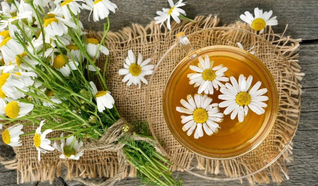 Чай в стеклянной чашке на столе с ромашкой