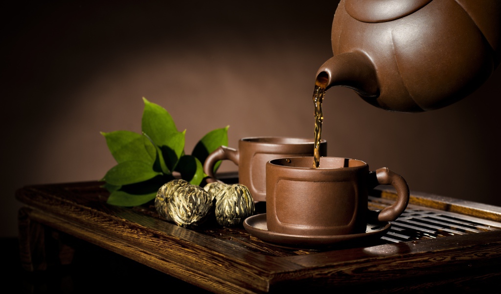 Чай наливают из чайника в коричневую чашку