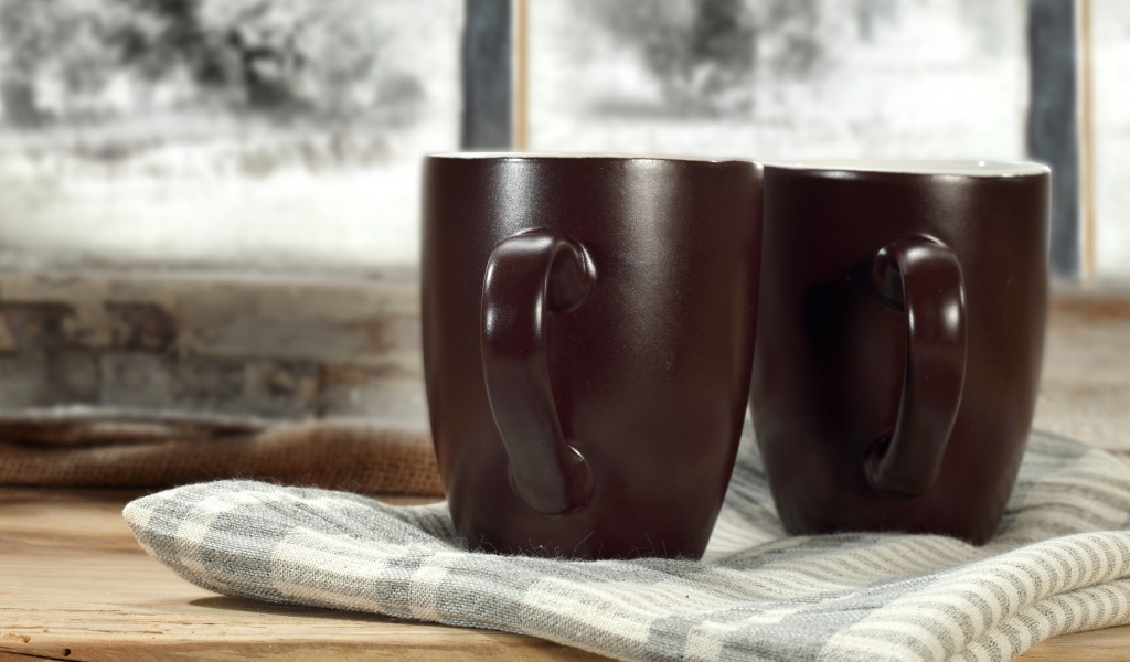 Две коричневые чашки кофе на столе с шарфом