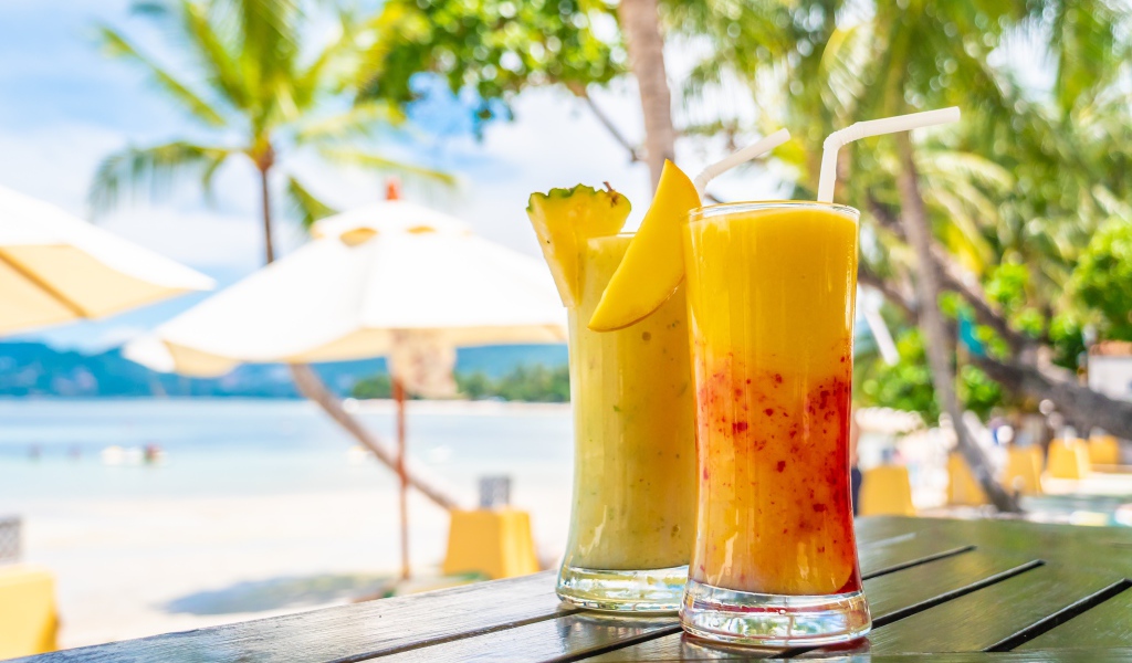 Два цитрусовых коктейля на столе на тропическом пляже