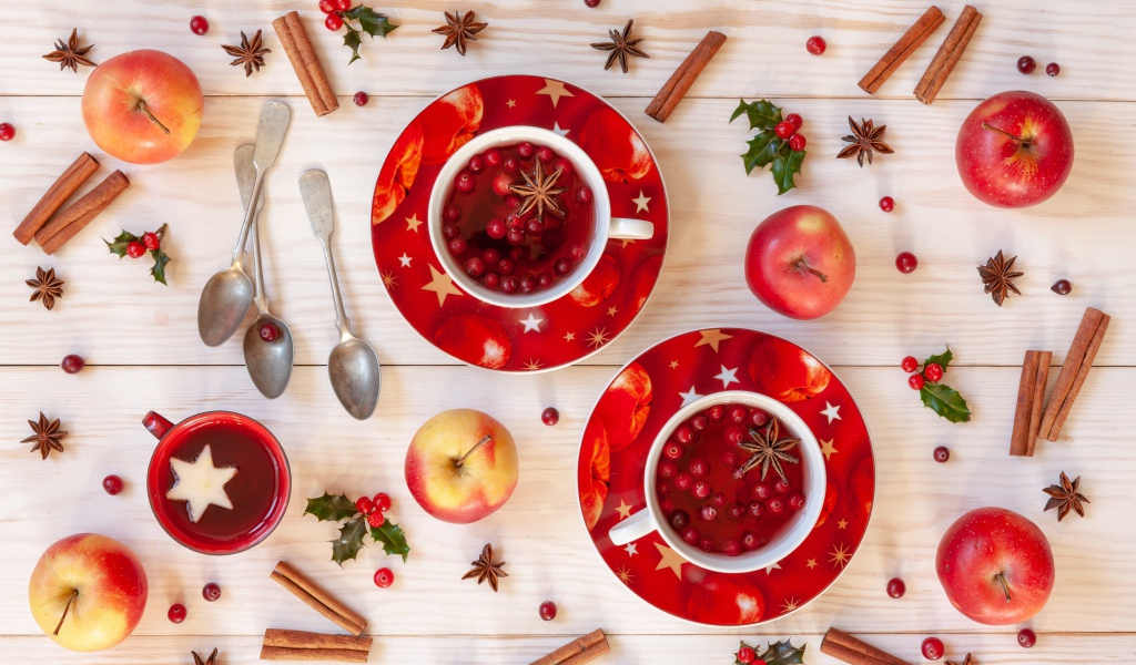 Две чашки клюквенного чая на столе с корицей, яблоками и бадьяном