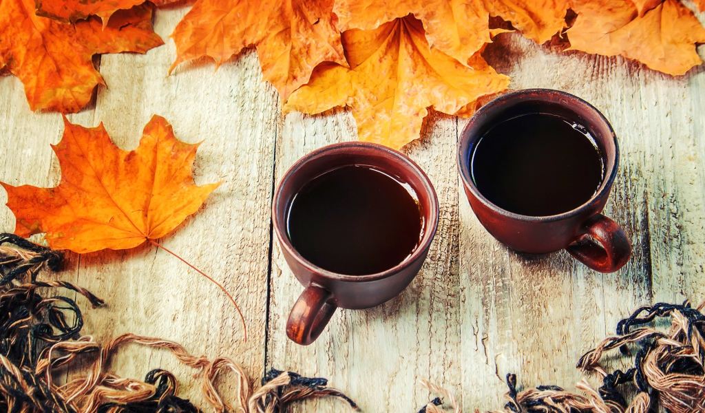 Две чашки горячего кофе на столе с сухими листьями