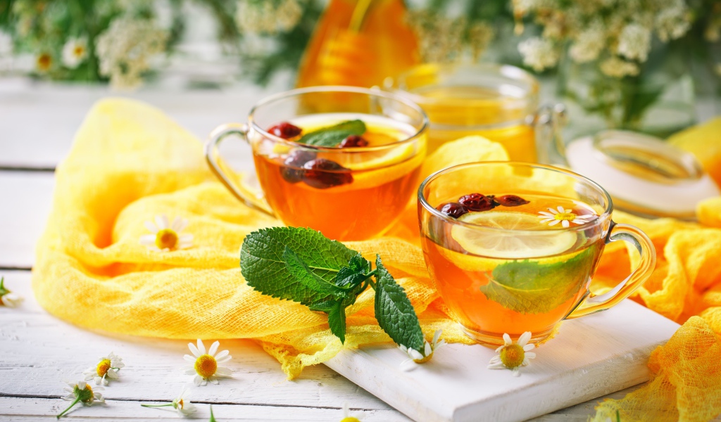 Две стеклянные чашки чая с лимоном, мятой и шиповником