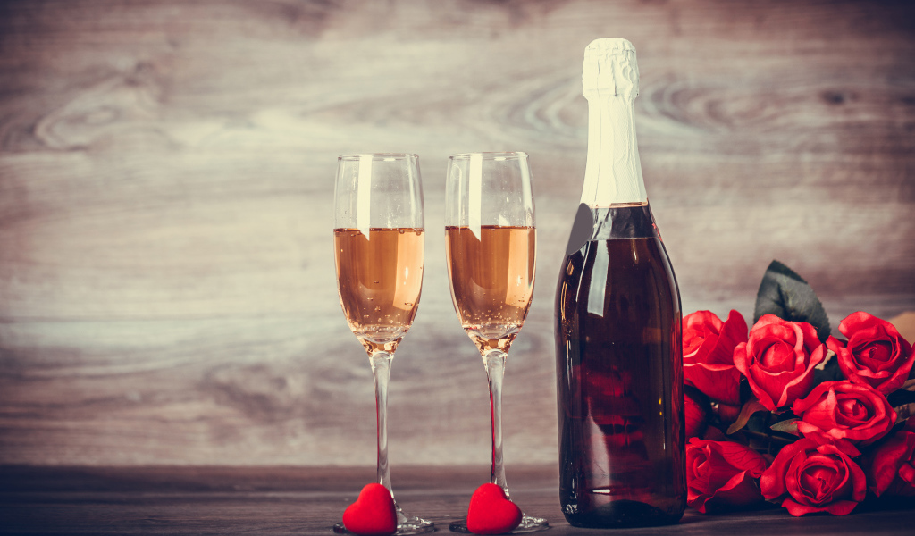 Два бокала и бутылка шампанского на столе с букетом роз