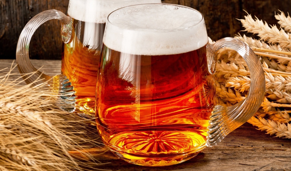 Два бокала пива на столе с колосьями пшеницы