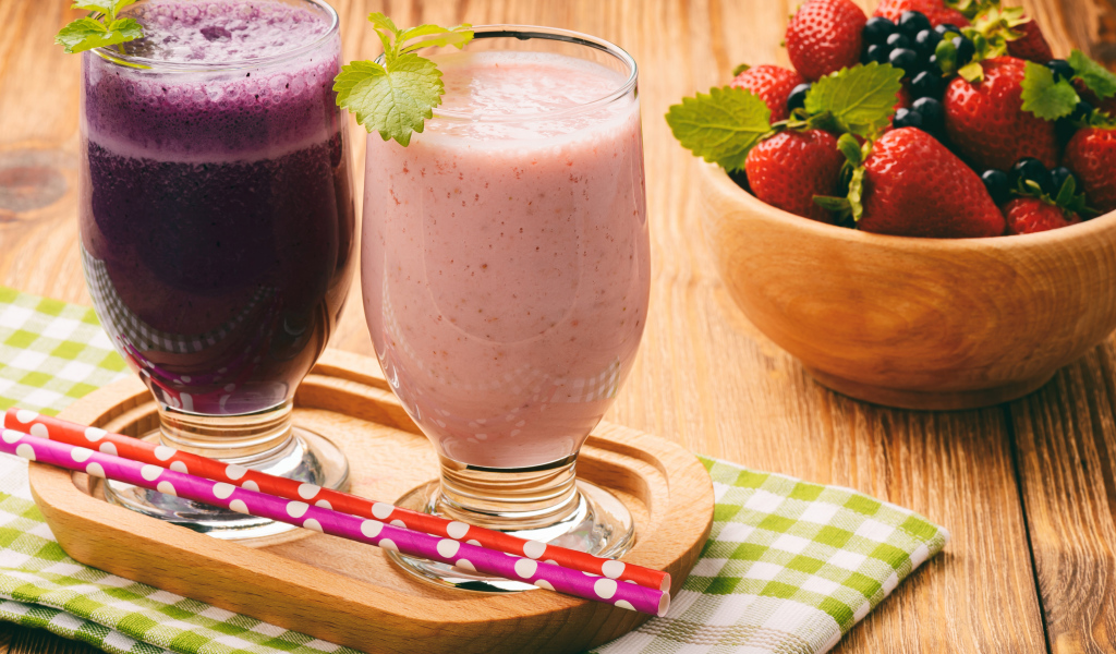 Два стакана смузи на столе с ягодами