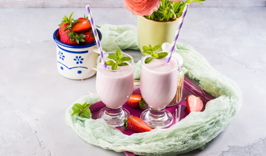 Два стакана с коктейлем на столе с букетом и клубникой