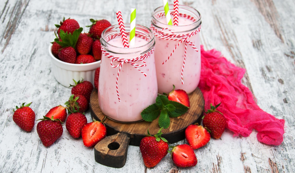 Две банки смузи стоят на доске на столе с клубникой