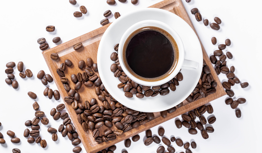 Белая чашка кофе на доске с кофейными зернами
