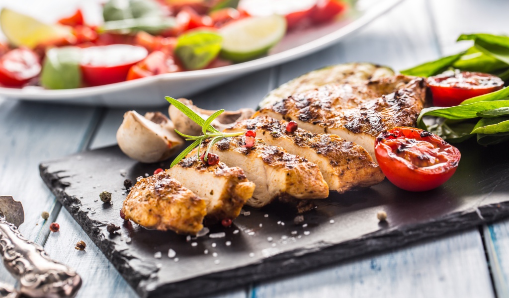 Запеченное куриное мясо на доске с помидорами 