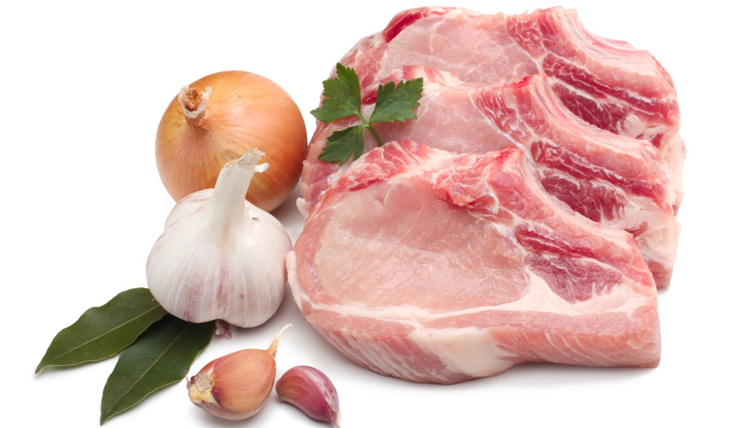 Куски мяса на белом фоне с луком и чесноком
