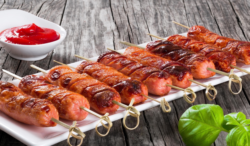 Сосиски гриль на шпажках на столе с соусом
