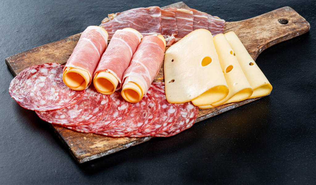 Ветчина на доске с колбасой и твердым сыром