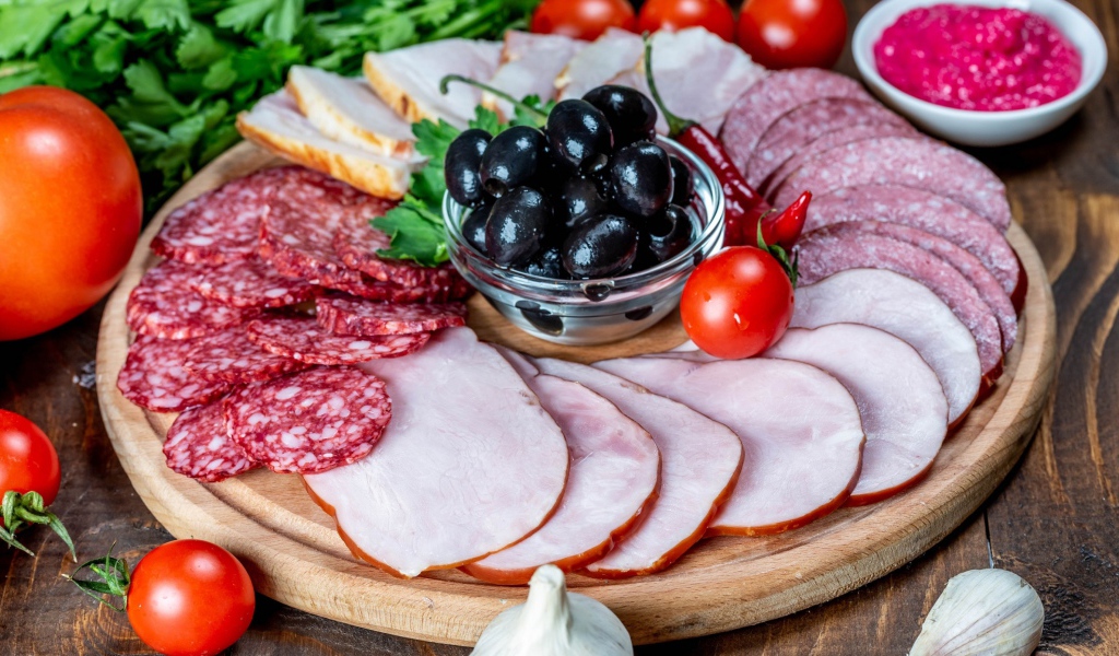 Колбасные продукты на доске с оливками