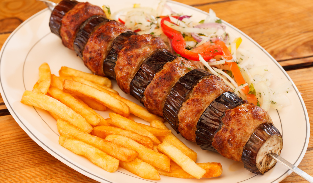 Шашлык с мясом и баклажанами на тарелке с картофелем фри 