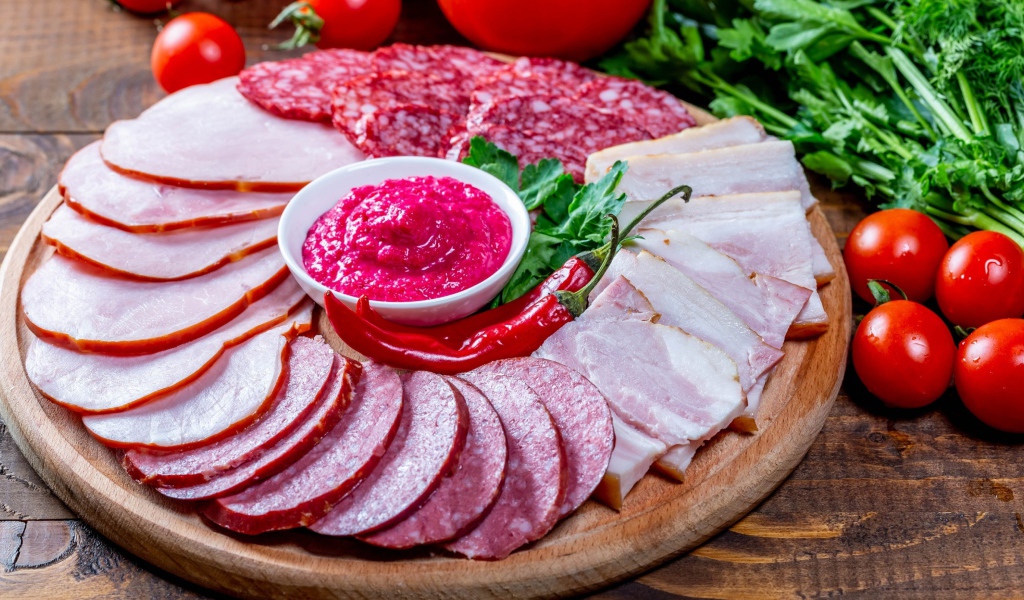 Мясная нарезка на доске с соусом, красным перцем,  помидорами и зеленью 