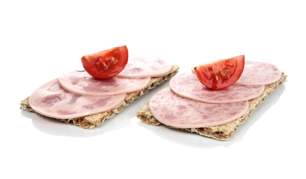 Тосты с колбасой и кусочками помидора на белом фоне