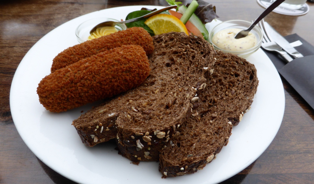 Два куска черного хлеба на тарелке с котлетами