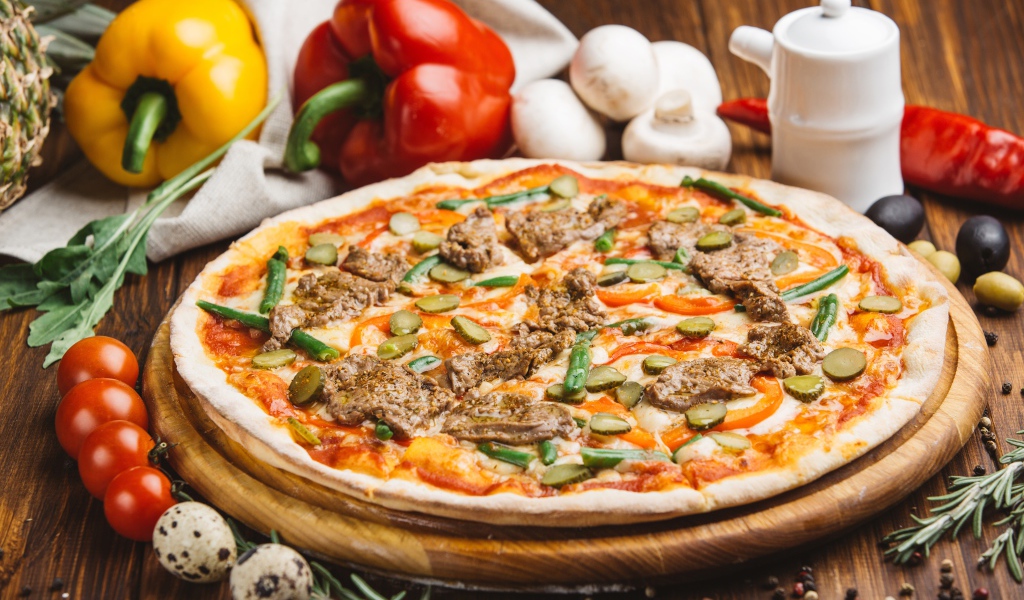 Свежая пицца с мясом и огурцами на столе с овощами