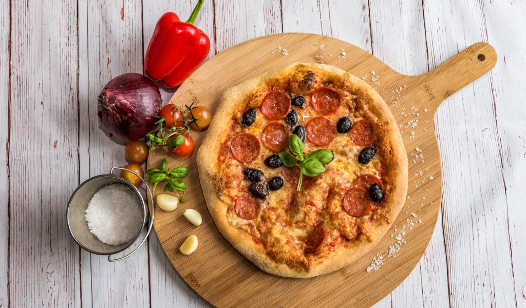 Пицца на доске с овощами и солью 