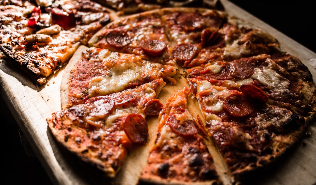 Пицца нарезана кусками на деревянной доске