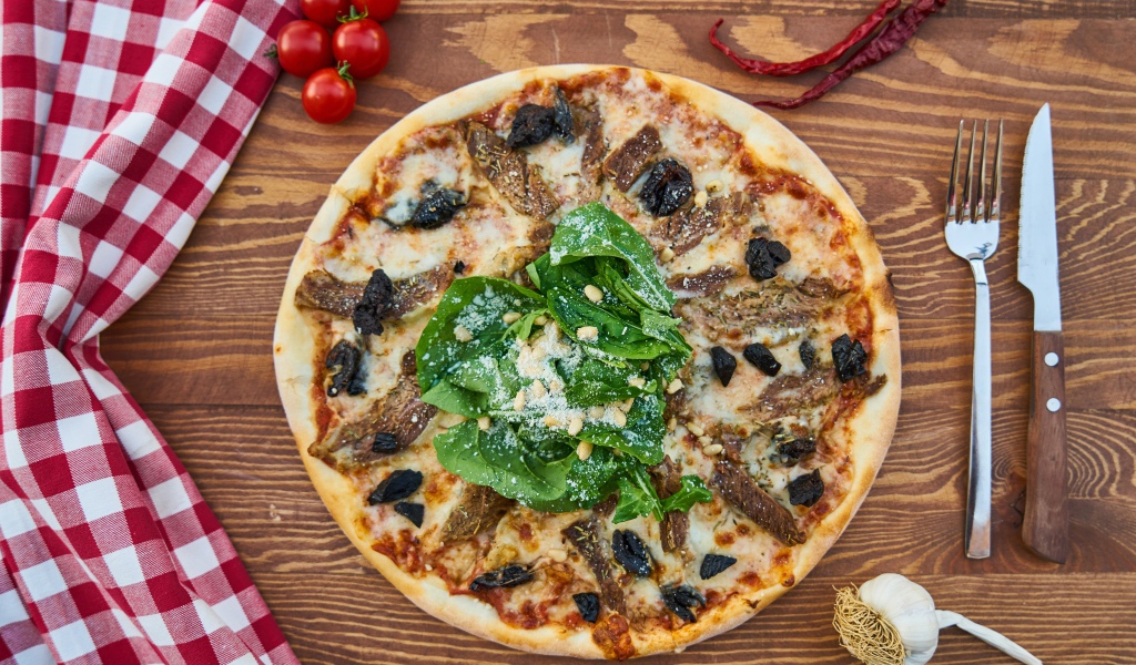 Пицца с мясом и шпинатом на столе 