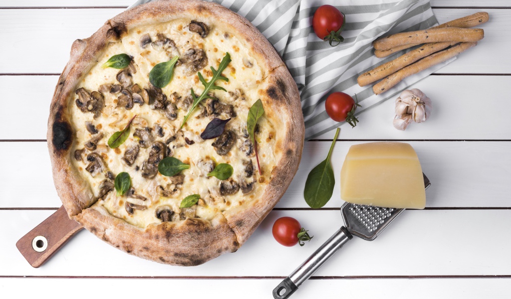 Пицца с грибами на столе с сыром и овощами