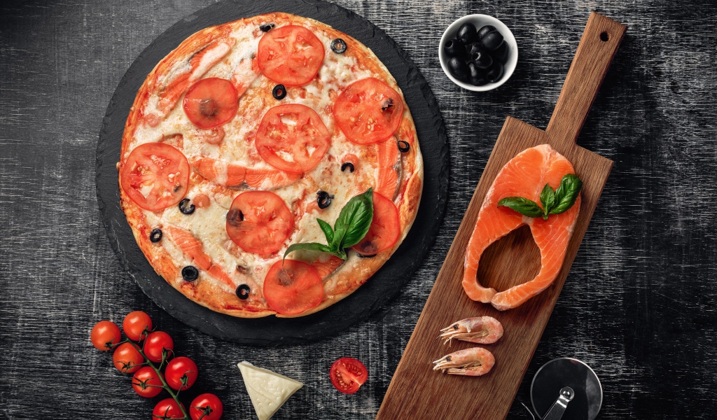 Пицца с помидорами, красной рыбой и сыром на столе 