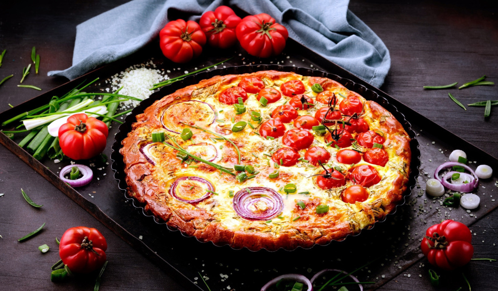 Пицца с помидорами и луком на подносе с овощами