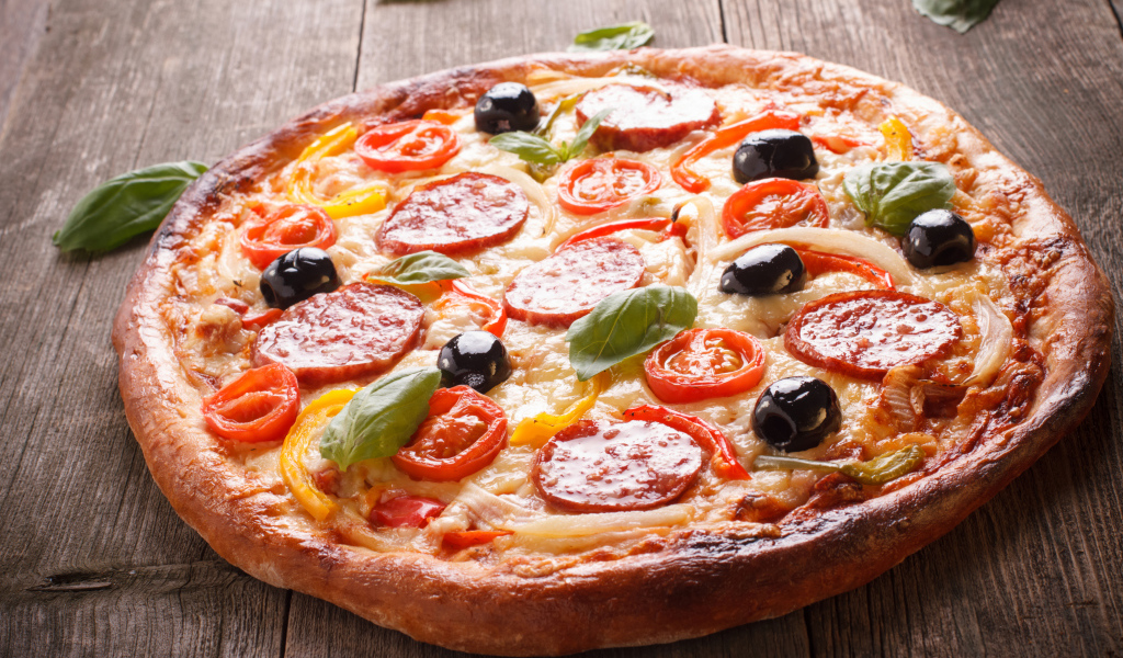 Румяная пицца с колбасой, помидорами, оливками и сыром