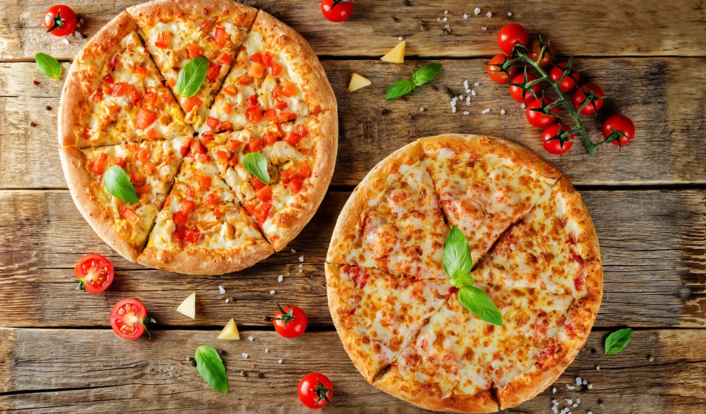 Две пиццы с сыром и болгарским перцем на столе с помидорами