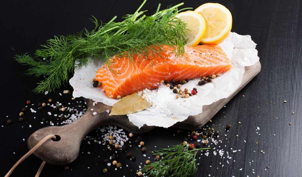 Кусок красной рыбы на доске с укропом и лимоном 