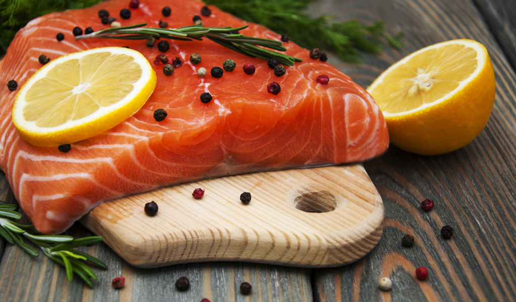 Кусок красной рыбы с лимоном и черным перцем