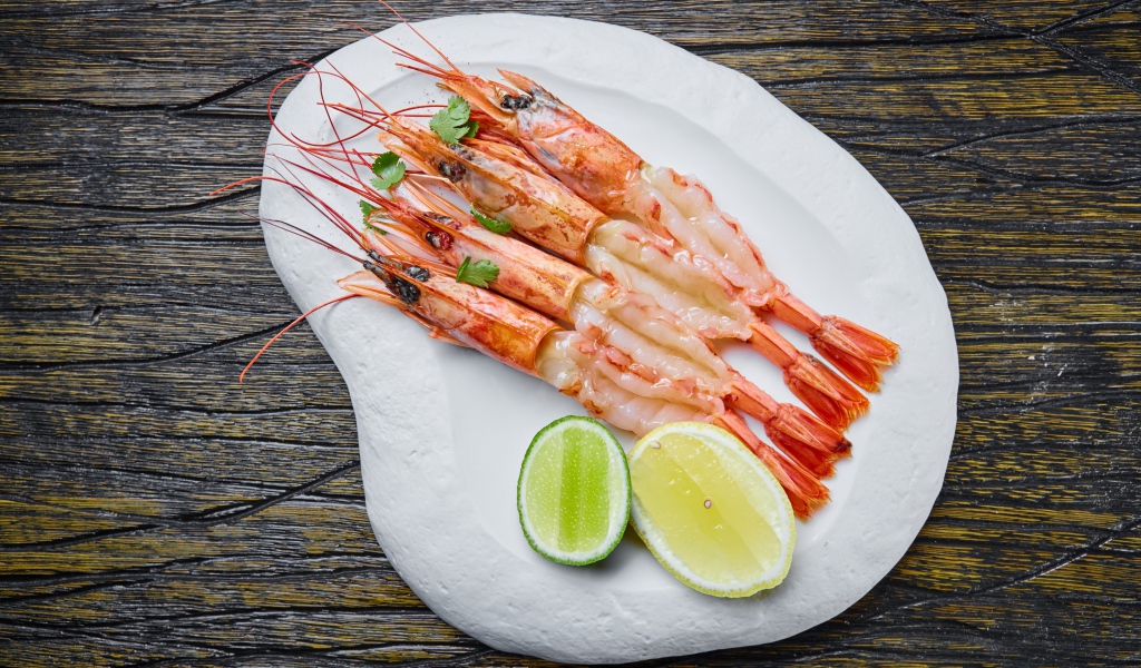 Аппетитные креветки на белой тарелке с лимоном