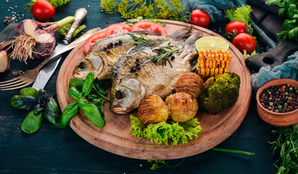 Baked fish on the cutting board with vegetables