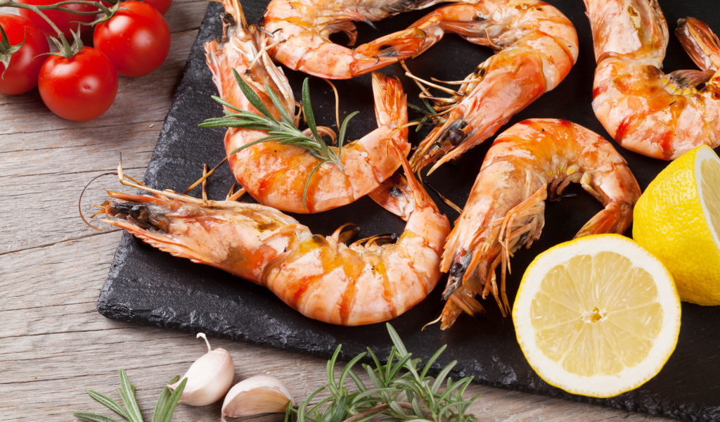 Вареные креветки на столе с лимонами и помидорами