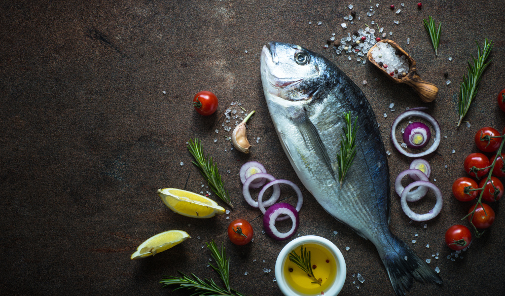 Свежая рыба на столе с овощами и специями 