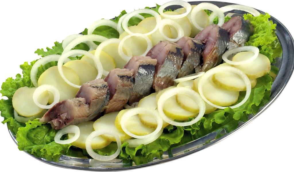 Сельдь с вареным картофелем, луком и листьями салата на белом фоне