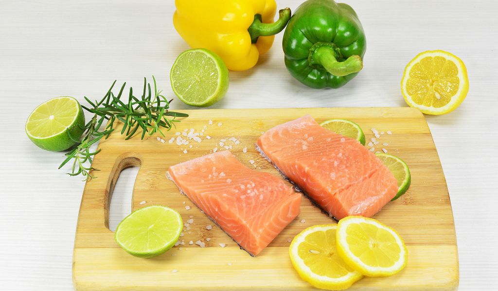 Red fish on a cutting board with lemon and pepper