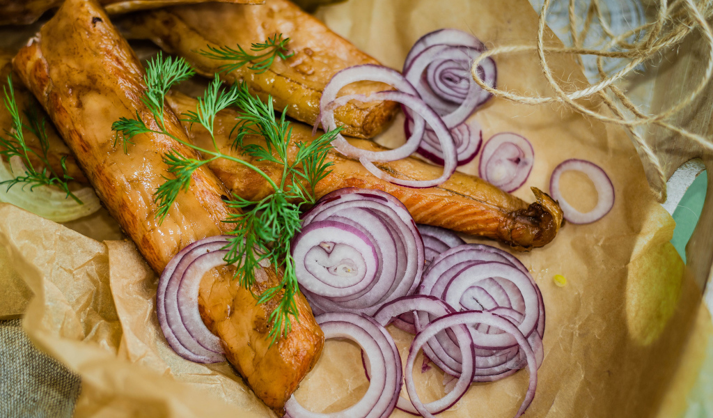 Копченое филе рыбы на бумаге с луком