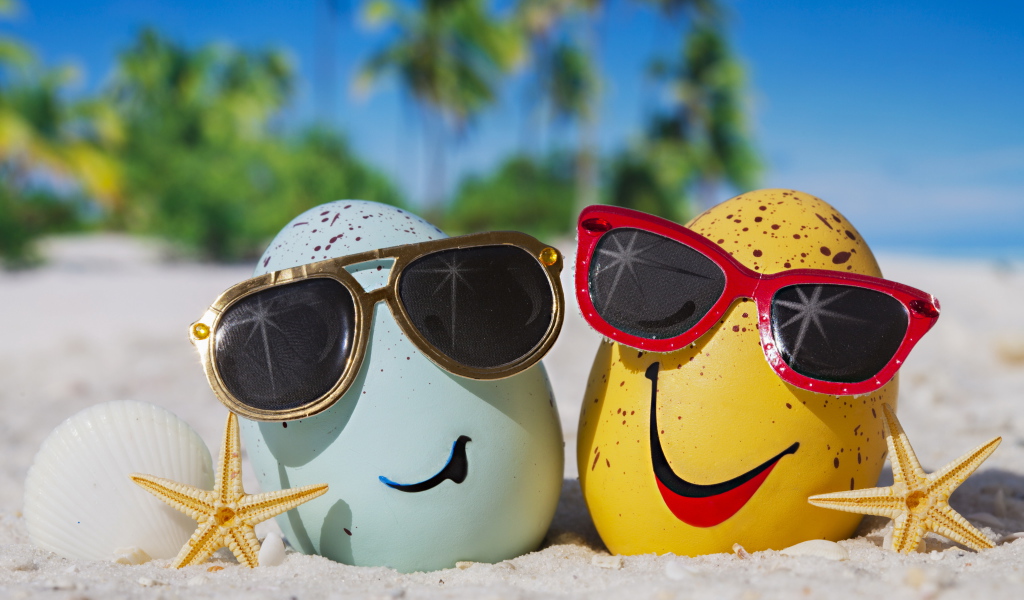 Два яйца в солнечных очках на морском песке летом