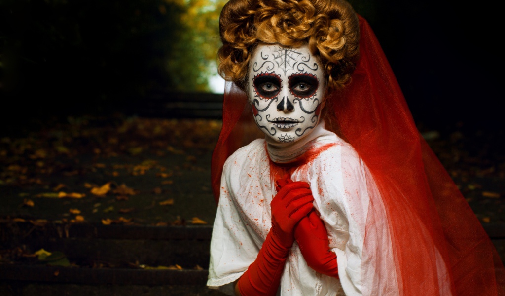 Девушка с маской на лице и красной фатой на праздник Хэллоуин 