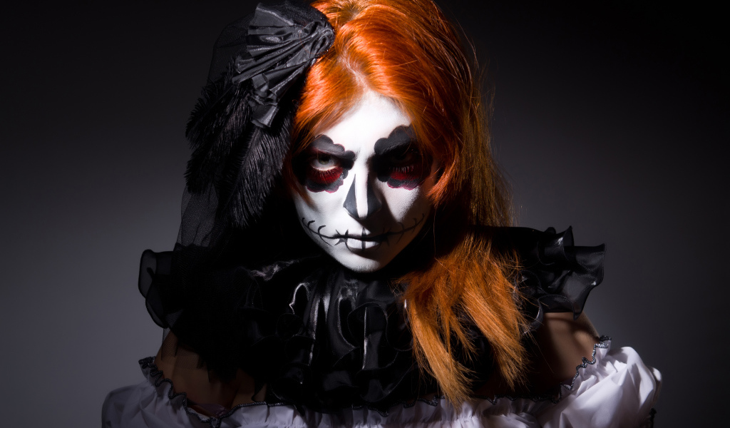 Рыжеволосая девушка с маской на лице на Хэллоуин 