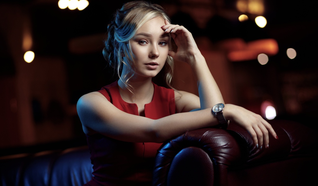 Красивая девушка с часами на руке сидит в кресле